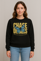 Person wearing a black sweatshirt with a butterfly graphic and text, Chase Dreams, on a plain background