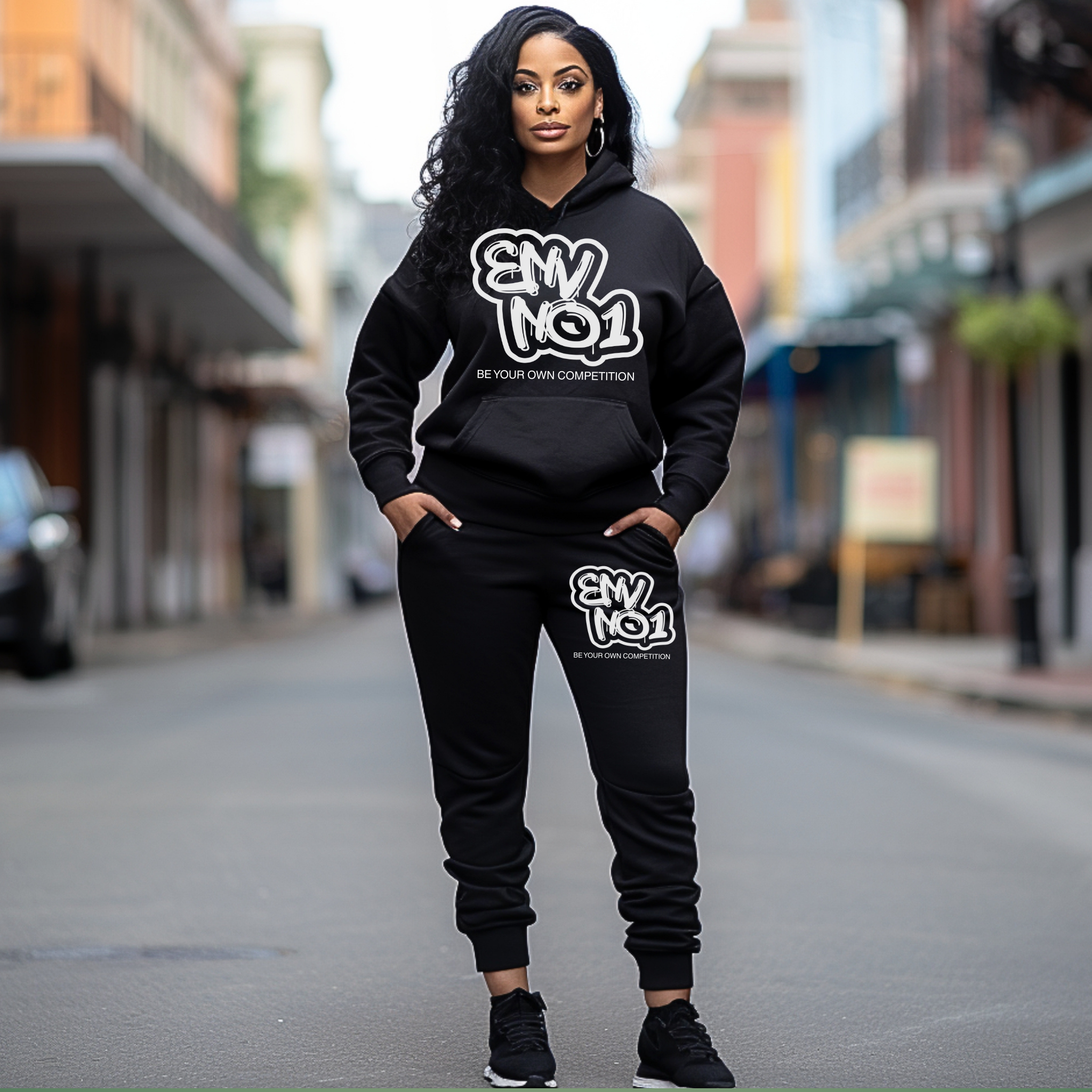 Woman wearing a black hoodie and pants with 'ENVNO1' branding on a city street.
